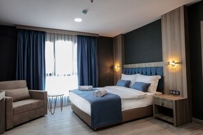 Une chambre d’hôtel moderne avec un grand lit, un canapé, une petite table et une table de chevet.