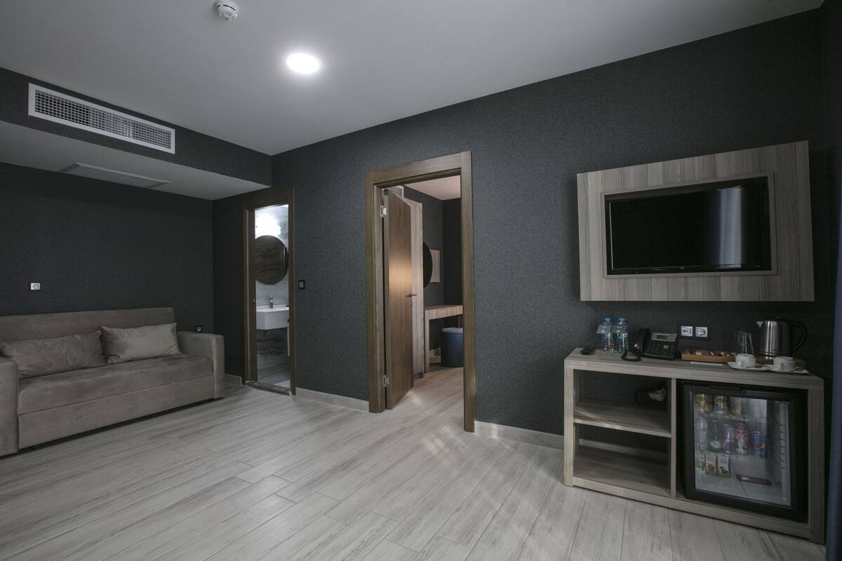 Una sala de estar moderna con un sofá, un televisor montado en la pared y un mueble bajo con varios objetos.