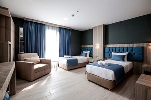 Une chambre d’hôtel moderne avec deux lits, un canapé, une petite table et un bureau.