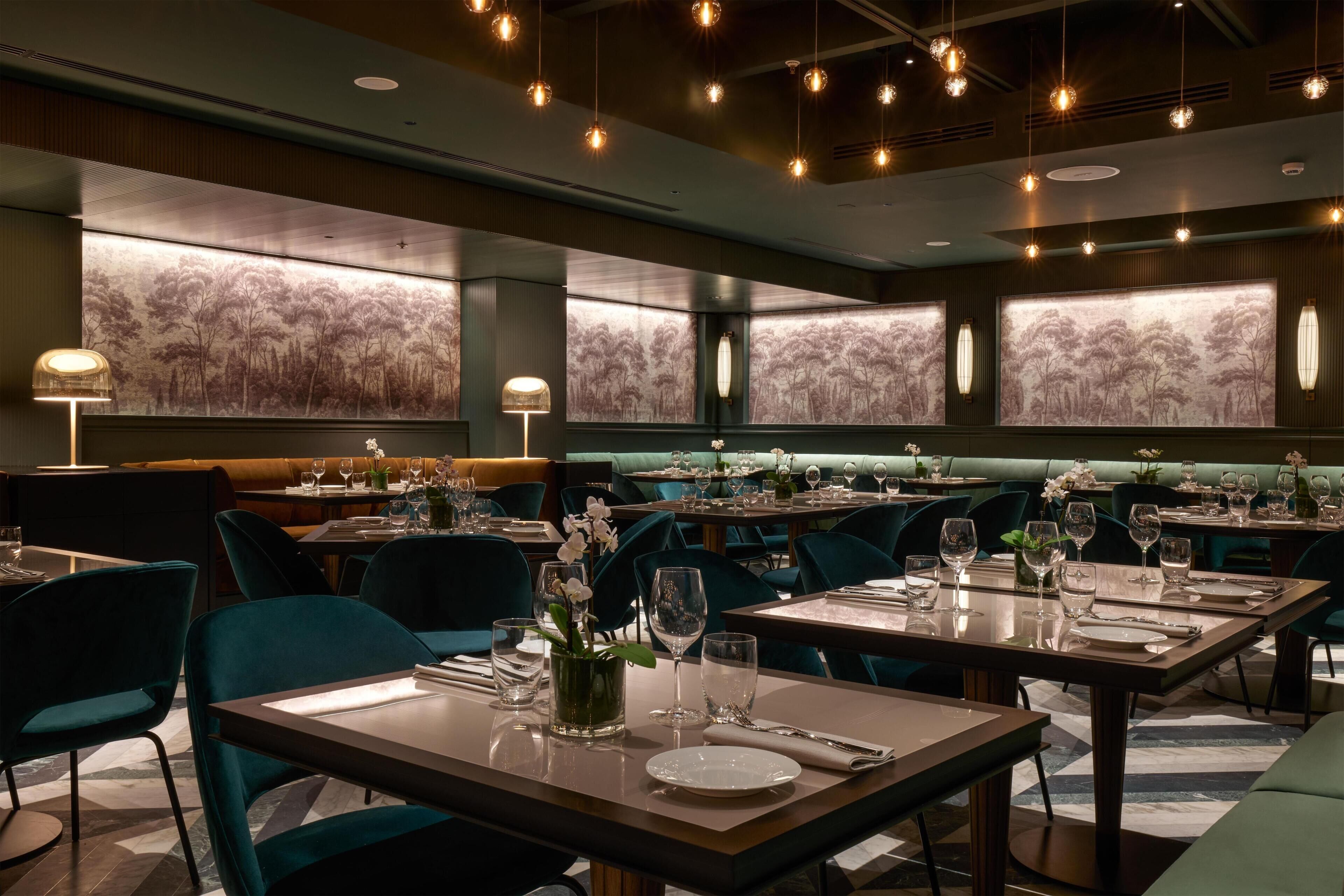 Un restaurante con varias mesas, sillas y un amplio mural en la pared.