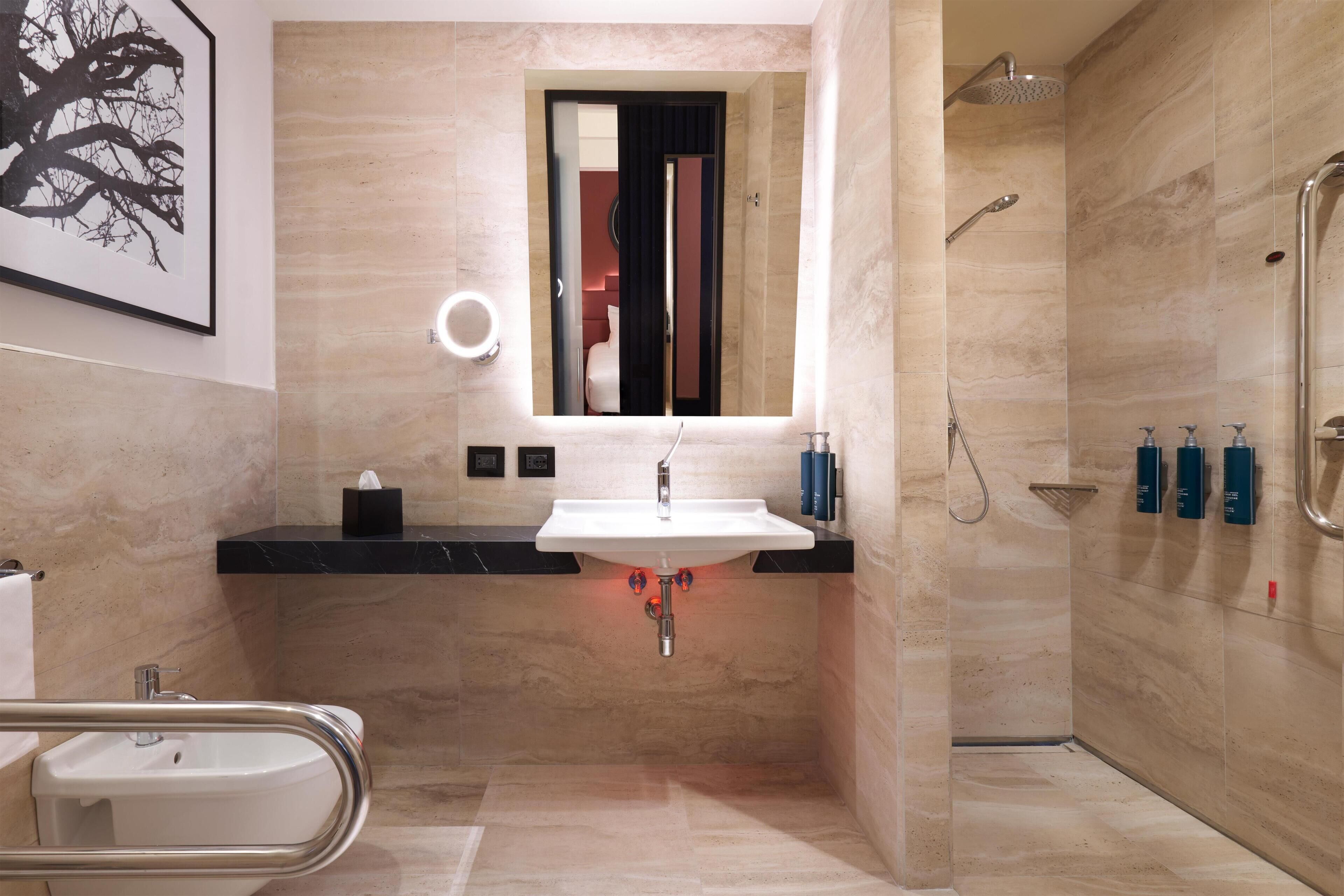 Un baño moderno con lavamanos, espejo y ducha.