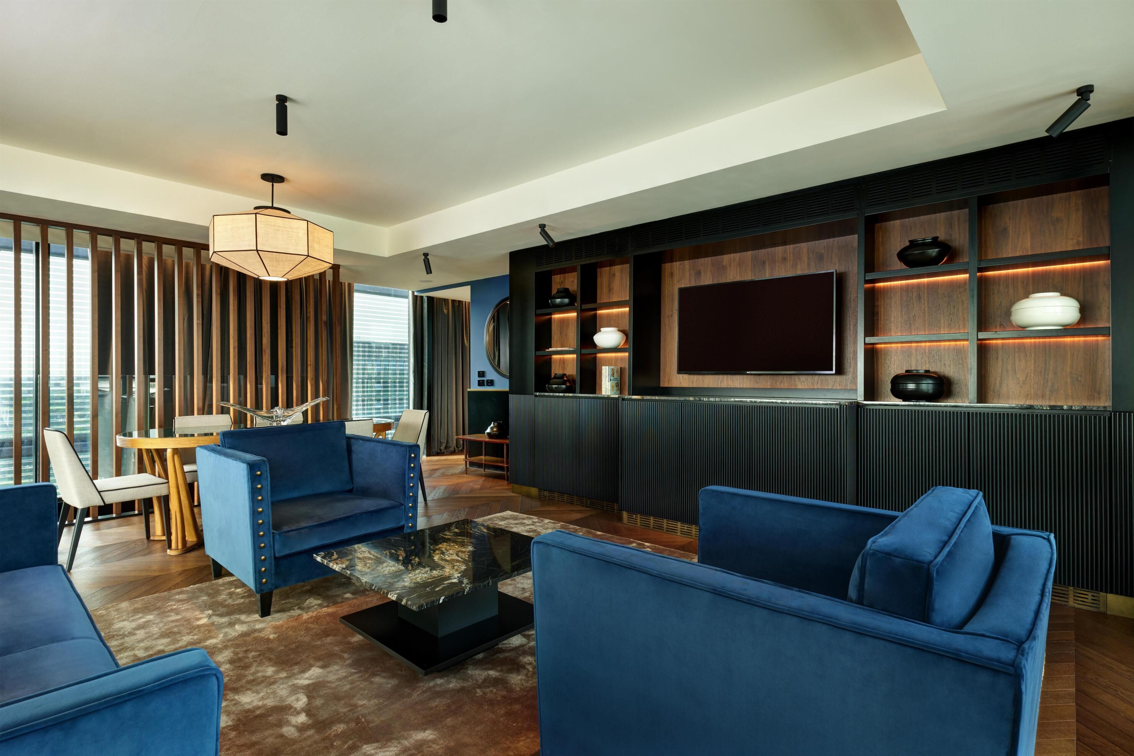 Ein modernes Wohnzimmer mit blauen Sofas, einem Couchtisch und einer TV-Wand.