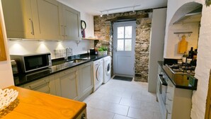 Une cuisine compacte équipée d’un lave-linge, d’un four à micro-ondes et d’une cuisinière.