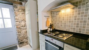 Une cuisine équipée d’un four Bosch, d’une cuisinière à gaz et d’un mur en pierre.