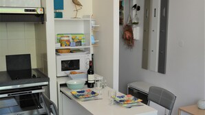 A compact kitchen with a dining table, chairs, a microwave, a small oven, and a refrigerator. - Duplex studio 2 steps from Carcans-Maubuisson lake (Carcans)