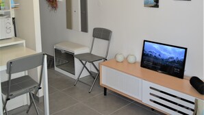 A modern, well-lit room with a desk, chairs, a television, and wall-mounted pictures. - Duplex studio 2 steps from Carcans-Maubuisson lake (Carcans)