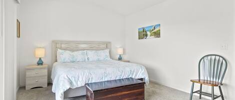 A bedroom with a bed, bedside tables, a bench, a chair, and a ceiling fan.