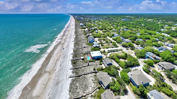 An aerial view of a coastal residential area with a beach, houses, and greenery. - Sea Chique | Ocean View Beach House with Private Pool and Hot Tub (Surfside Beach)