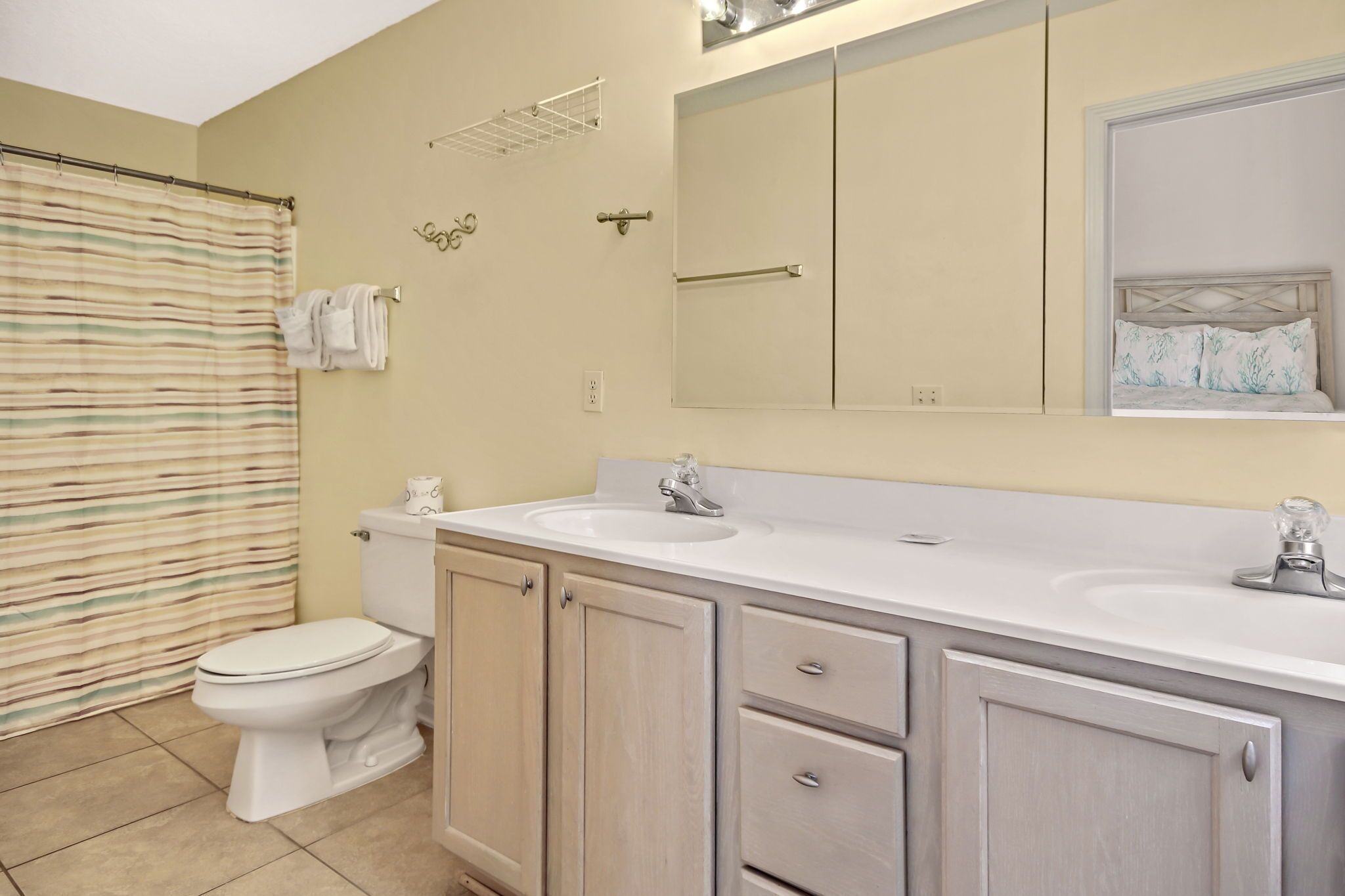 A bathroom with a toilet, two sinks, a mirror, and a shower curtain.