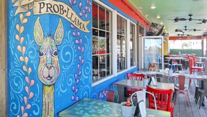 A restaurant with colorful murals, outdoor seating, and ceiling fans. - Sea Chique | Ocean View Beach House with Private Pool and Hot Tub (Surfside Beach)