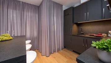 A modern kitchen with dark cabinets, a marble countertop, and a wooden floor.