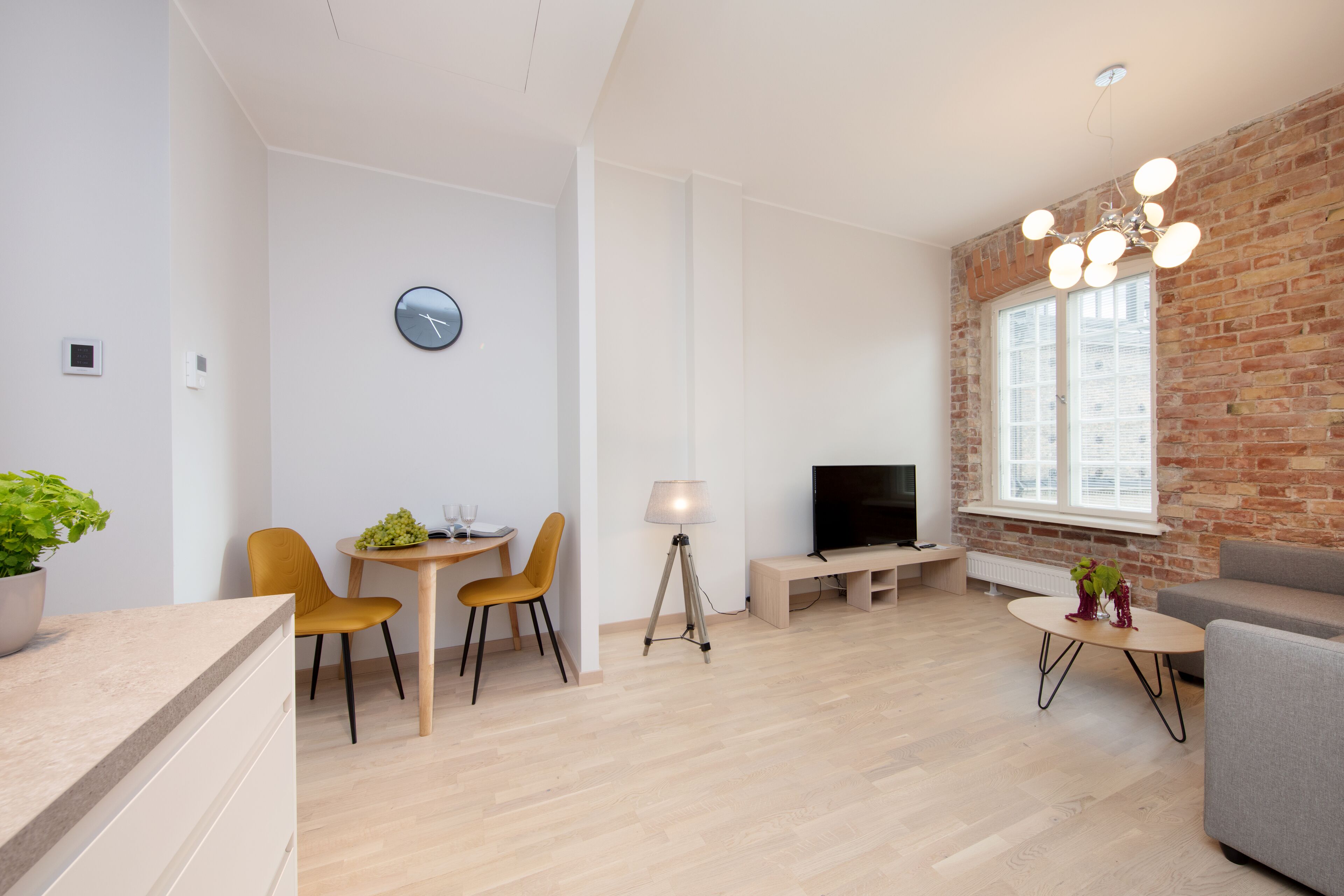 Un salon moderne avec un coin repas, un téléviseur et un mur en briques.
