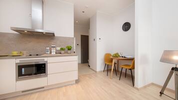 A modern kitchen with a built-in microwave, a stainless steel range hood, and a dining area with a table and chairs.