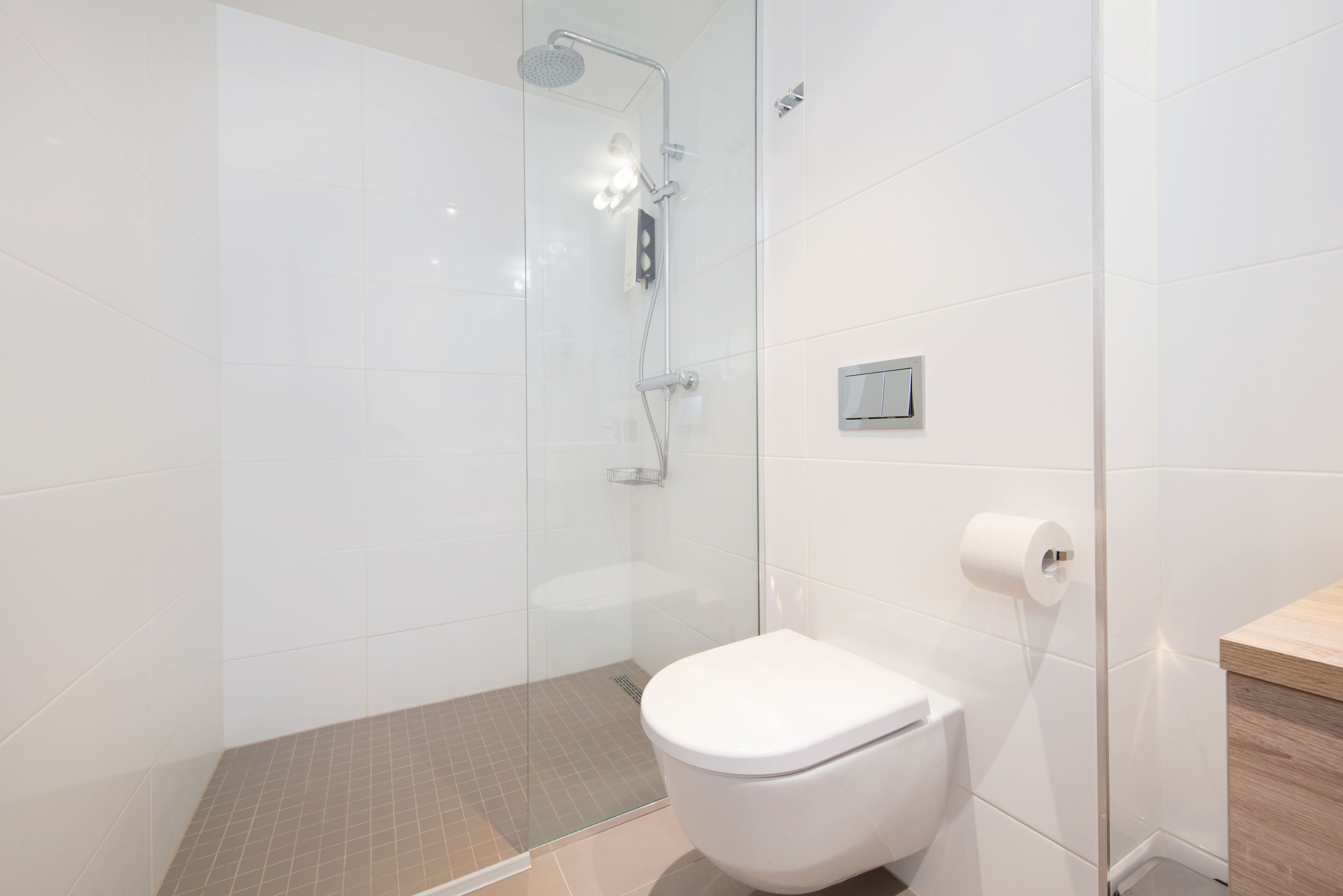 A modern bathroom with a glass-enclosed shower, a white toilet, and a wooden vanity.