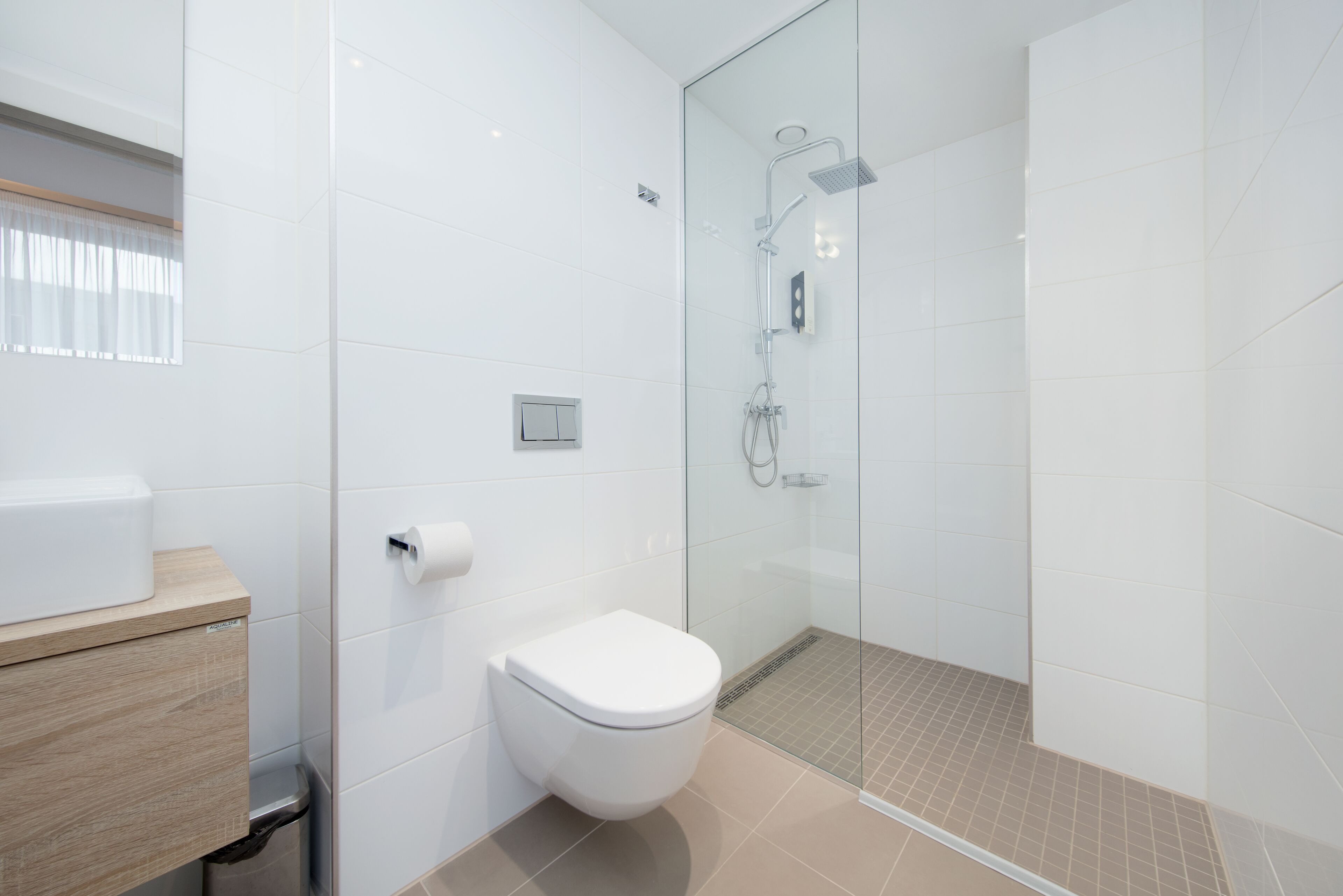 A modern bathroom with a toilet, a shower, and a sink.