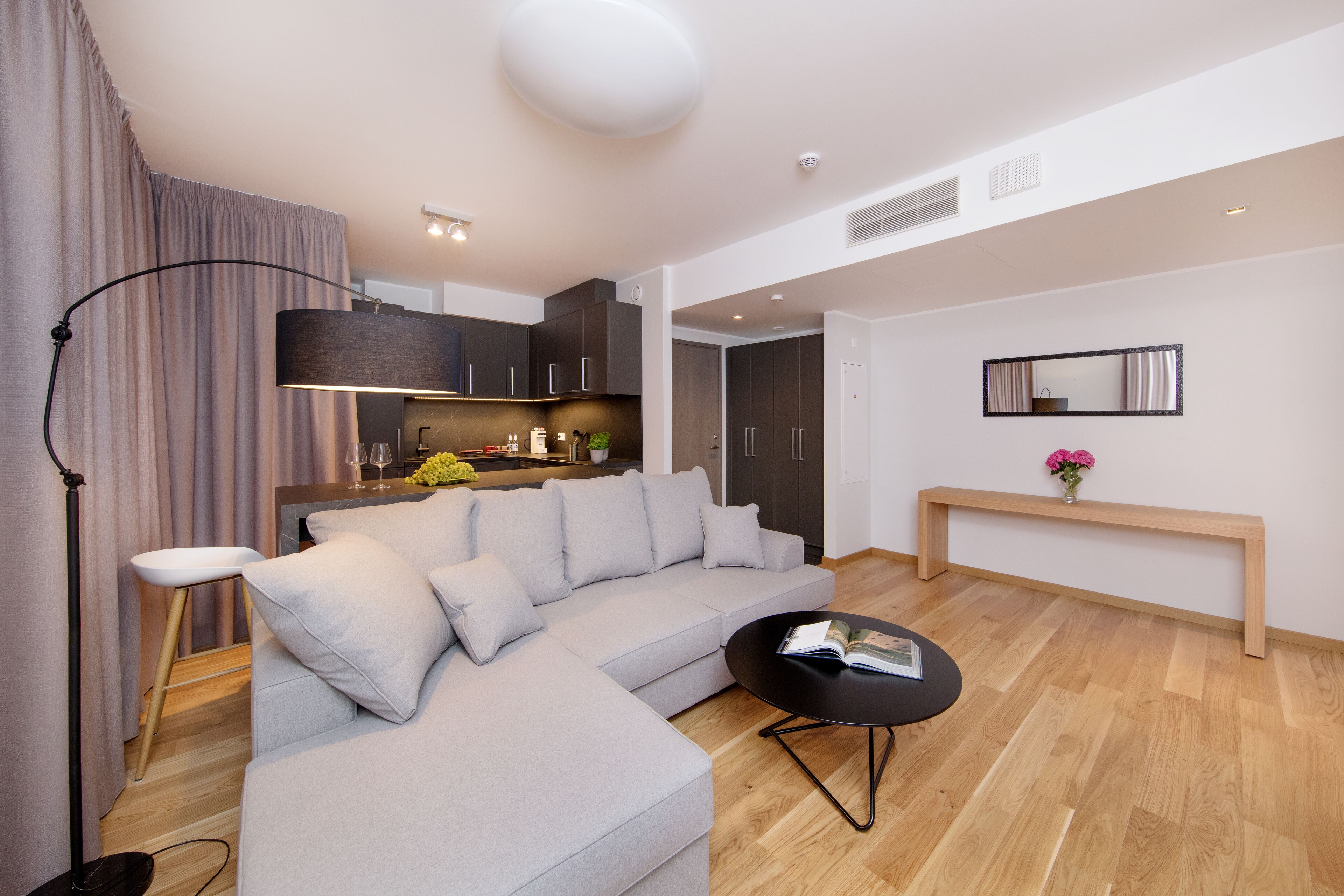 A modern living room with a grey sectional sofa, a black coffee table, and a wooden bench.