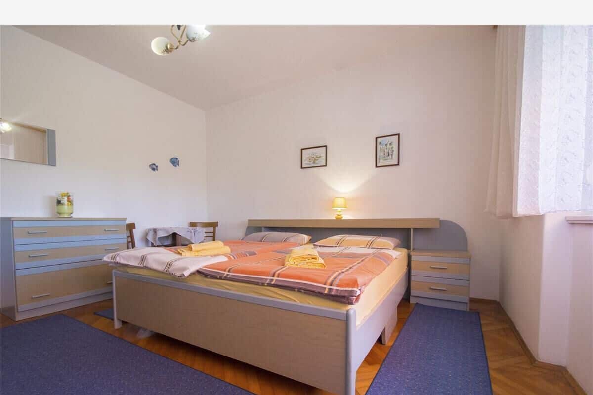 A bedroom with a bed, bedside tables, a dresser, and a lamp.