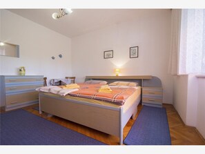 Et soveværelse med seng, sengeborde, kommode og lampe.