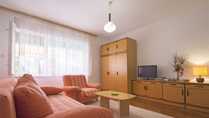 A living room with a sofa set, a coffee table, a TV, and wooden cabinets. - Apartments Andrea (Crikvenica)