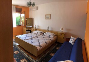 A bedroom with a bed, a sofa, a dresser, and a nightstand.