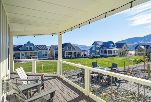 A covered outdoor area with Adirondack chairs and a view of blue houses in the background.