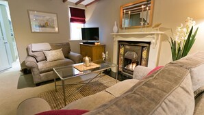 Ein gemütliches Wohnzimmer mit Kamin, einer Couch, einem Glastisch und einem Fernseher.