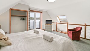A bedroom with a large bed, a red chair, a wardrobe, and a television. - Creinch Lodge-Sleeps 2 - sleeps 2 guests  in 1 bedroom (Alexandria)