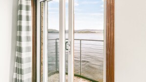 A room with a sliding glass door leading to a balcony with a view of a body of water and distant hills. - Creinch Lodge-Sleeps 2 - sleeps 2 guests  in 1 bedroom (Alexandria)