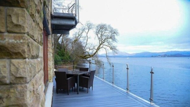 Une terrasse avec une table et des chaises donnant sur un plan d’eau.