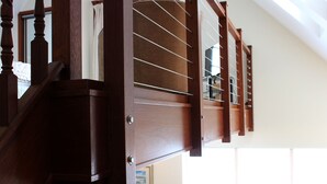 Un escalier en bois avec une rampe en verre, menant à l’étage supérieur.