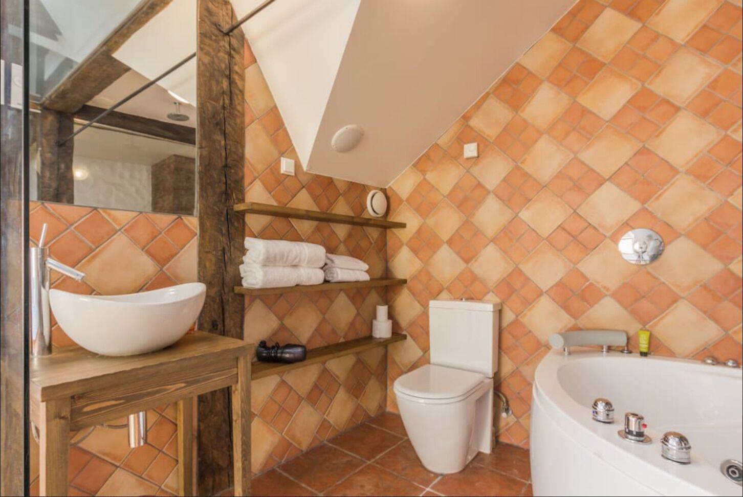 A bathroom with a white sink, a toilet, a bathtub, and a shelf with towels.