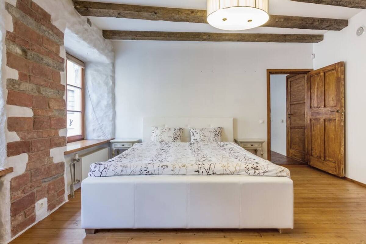 Ein Schlafzimmer mit einem großen Bett, Holzboden, Backsteinwand und Holztür.