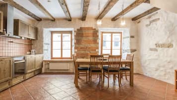 Una cocina rústica con vigas a la vista, una mesa de comedor con sillas y una pared de piedra.