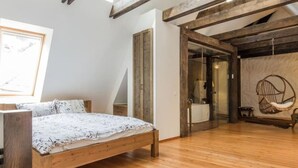 A bedroom with a wooden bed, a large window, and a view of the bathroom. - Blacksmith Old Town Apartments (Tallinn)