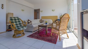 A living room with a sofa, two wicker chairs, a coffee table, and a red rug. - Apartments Gordana (Crikvenica)