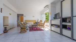 A modern living room with a sofa, two rocking chairs, a coffee table, and a TV. - Apartments Gordana (Crikvenica)