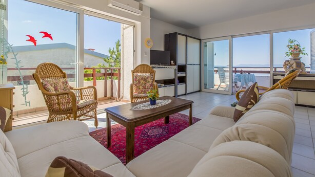 A spacious living room with a large sofa, two wicker chairs, a coffee table, and a balcony with a view. - Apartments Gordana (Crikvenica)