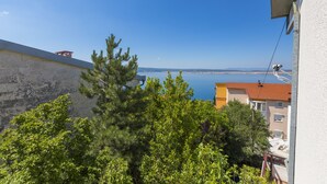 A coastal view with a clear sky, a building with a red roof, and a balcony overlooking the sea. - Apartments Gordana (Crikvenica)