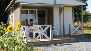 Ein kleines, eingeschossiges Gebäude mit einer überdachten Veranda und einem Tisch mit Stühlen.