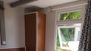 Ein Schlafzimmer mit Bett, Fenster und Kleiderschrank.