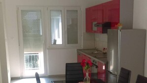 A dining area with a table set for six, six chairs, and a vase with flowers. - Apartments Iva (Crikvenica)