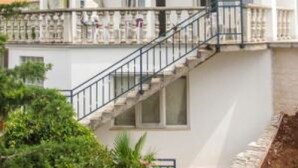 A two-story building with balconies, a staircase, and a garden area. - Apartments Silly (Crikvenica)