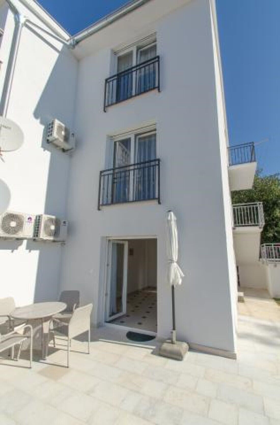 Un edificio de varios pisos con balcones, una zona de estar cubierta al aire libre y una puerta que da a un espacio interior.