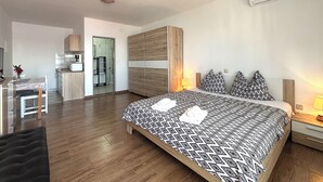 A modern hotel room with a large bed, a desk, and a kitchenette. - Apartments Silly (Crikvenica)
