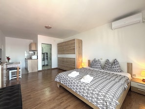 A modern hotel room with a large bed, a desk, and a kitchenette. - Apartments Silly (Crikvenica)