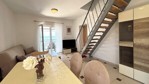 A modern living room with a dining table, sofa, and a staircase. - Apartments Silly (Crikvenica)