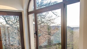 A corner room with a stone wall, a window with a view of trees, and a table with two chairs. - Apartment Milly (Vinodol)