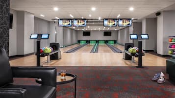 Un bowling doté de plusieurs pistes, de boules de bowling et d’un espace détente avec une table et des chaises.