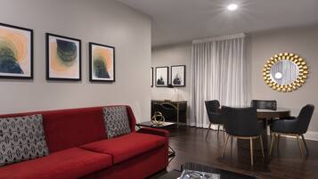 A modern living room with a red sofa, black chairs, a dining table, and framed artwork on the walls.