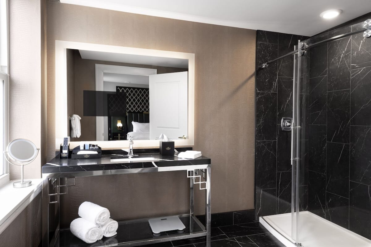 A modern bathroom with a glass shower enclosure, a vanity with a mirror, and neatly folded towels.